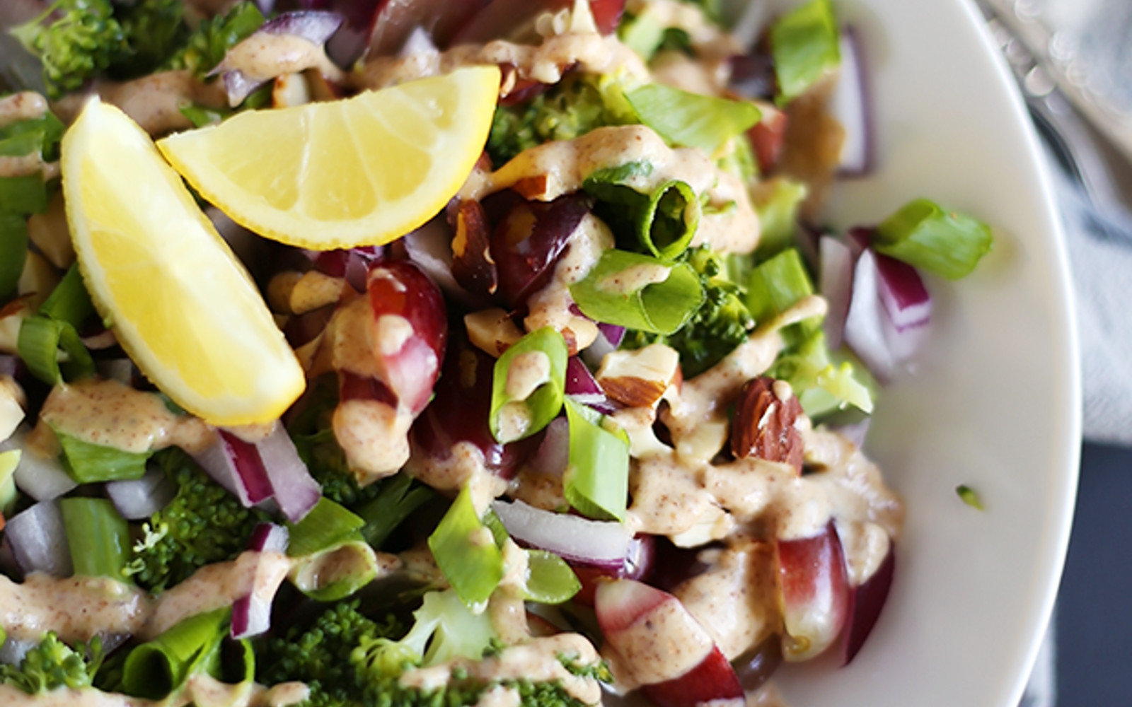 Vegan Gluten-Free Easy Broccoli Salad with almond lemon dressing topped with lemon wedges
