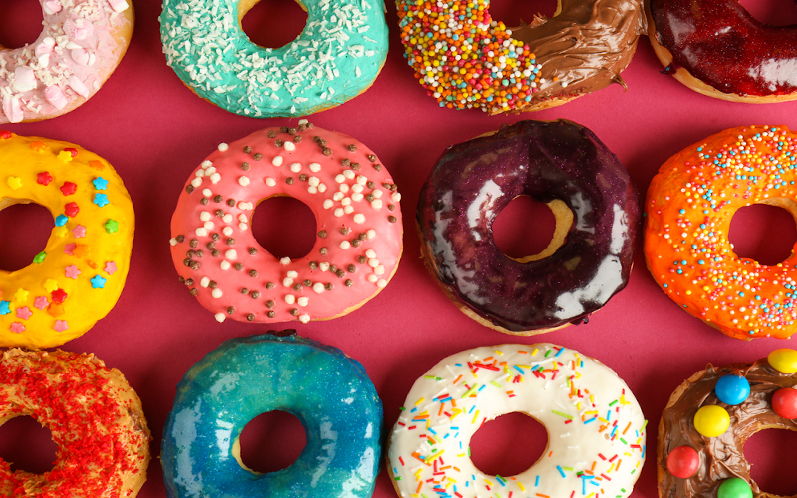 A variety of donuts set against a red background