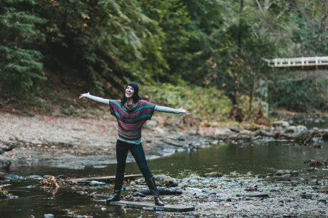 Woman standing in creek and spreading her arms wide