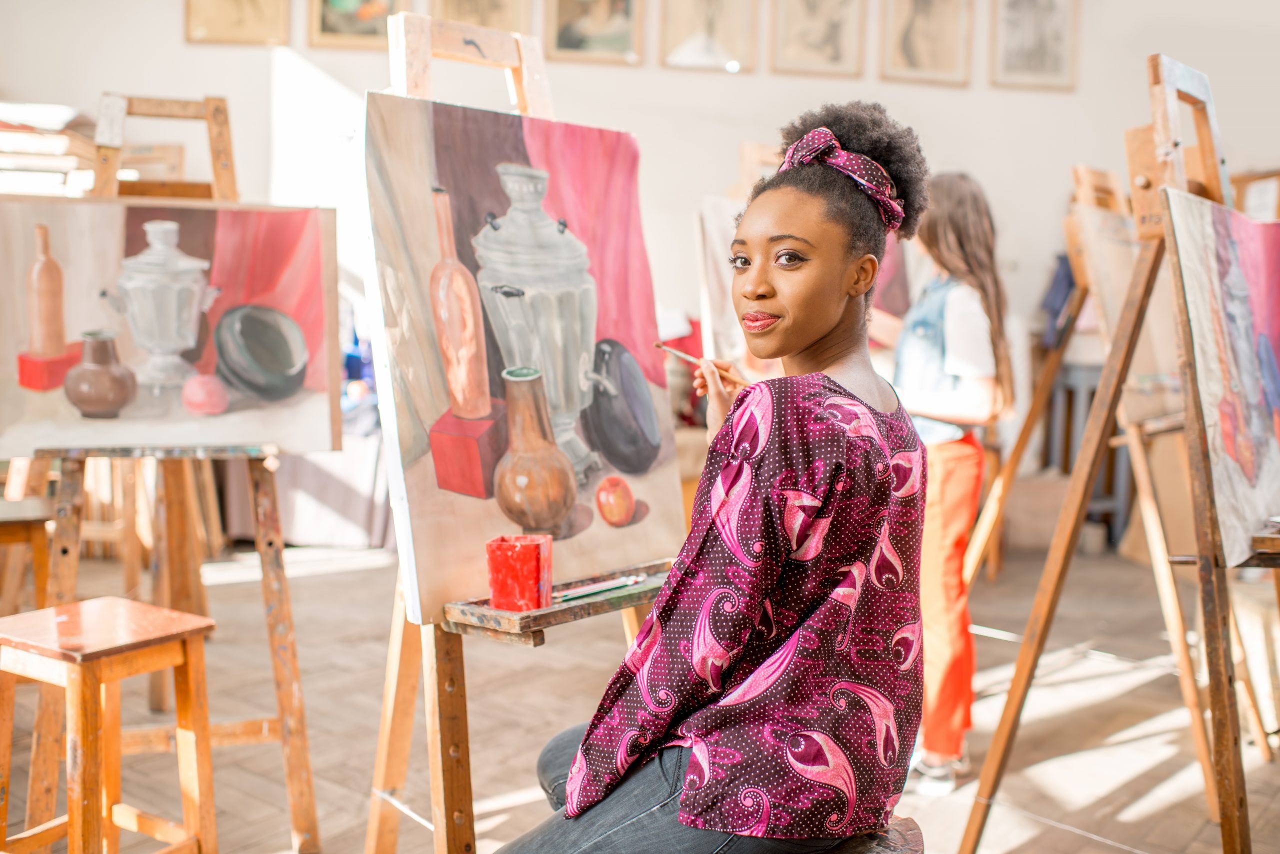 Portrait of a young african student sitting with still life painting at the studio
