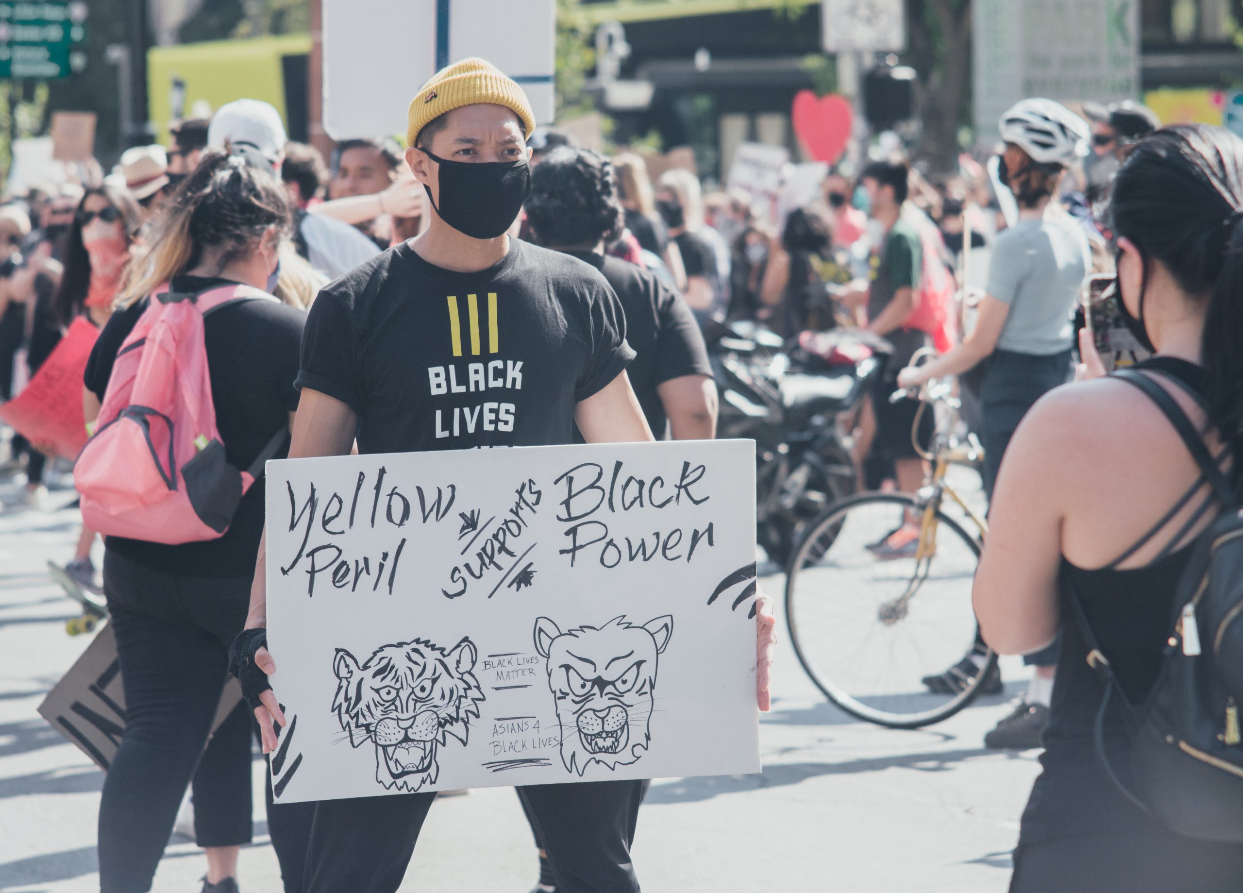 Man holds sign that reads "Yellow Peril Supports Black Power."