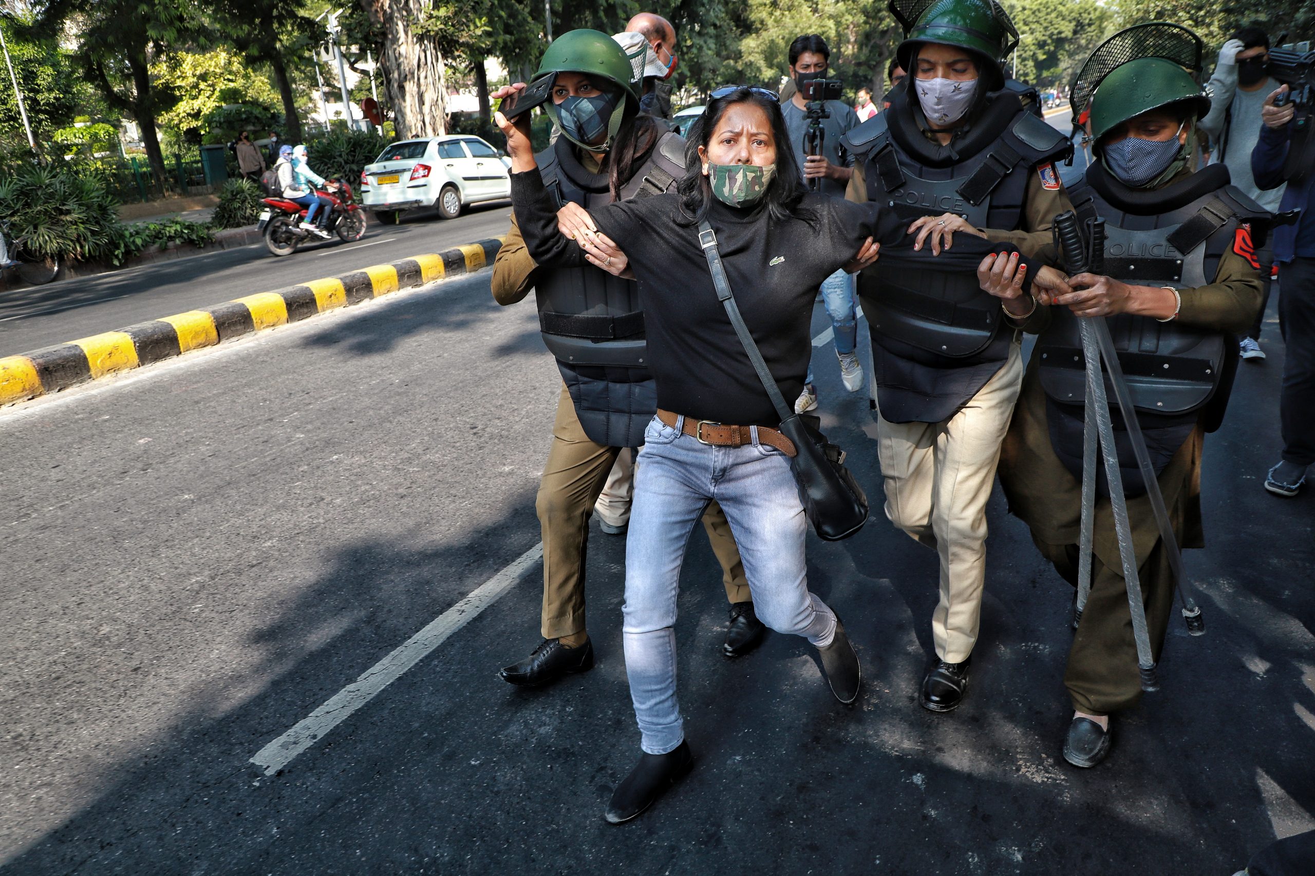 Woman wearing mask being arrested at a protest in India.