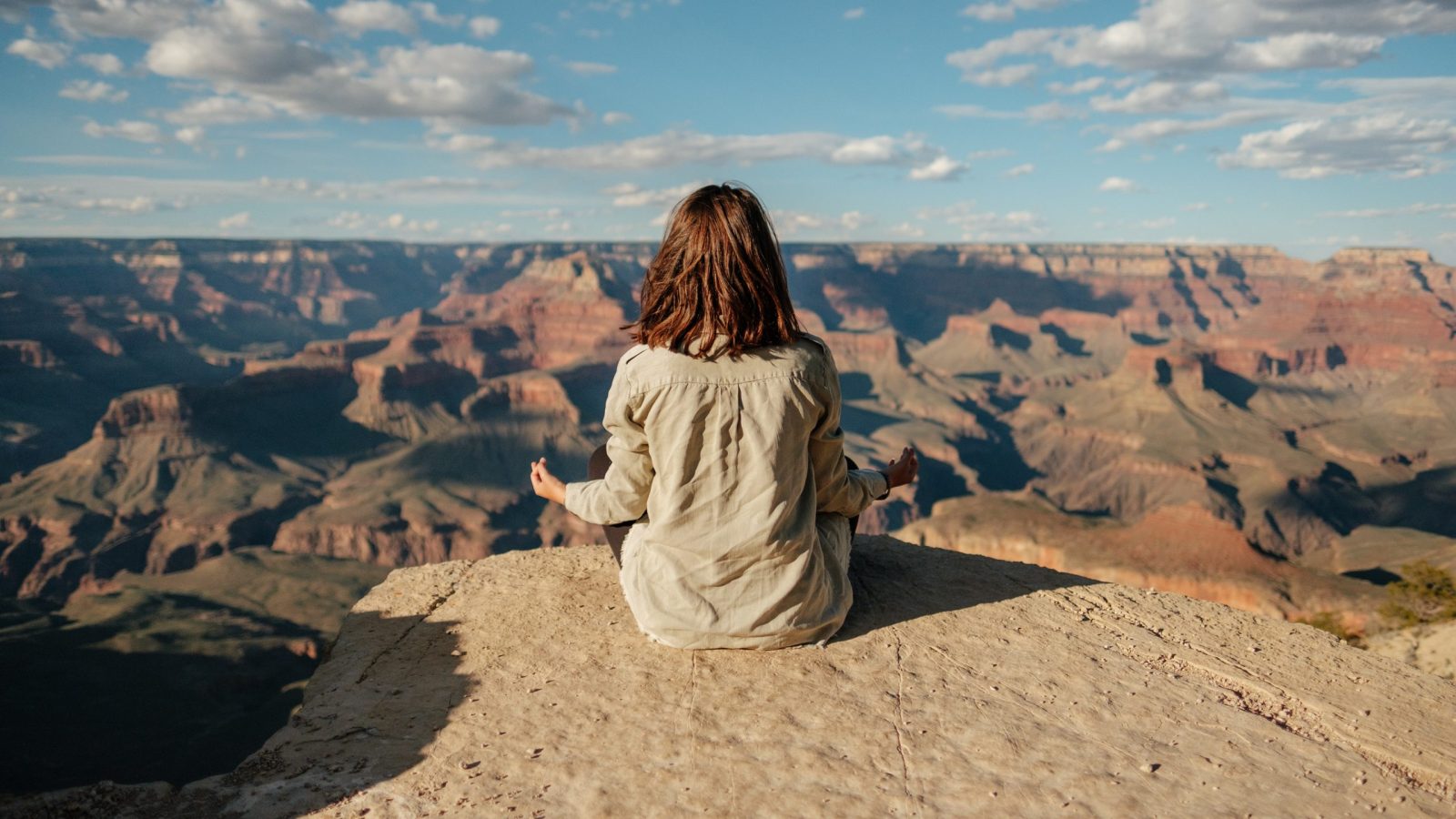 Someone meditating on the ground in front of a canyon
