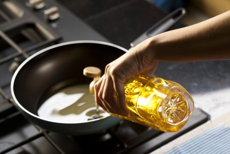 Someone pouring oil into a cooking pan