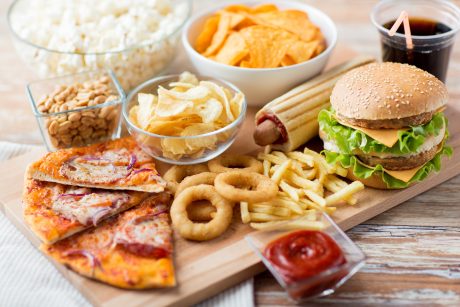 Numerous unhealthy foods on a wooden board