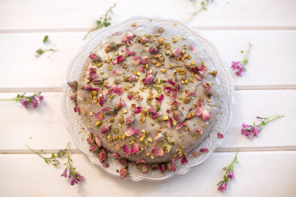 pistachio cake on a round plate with flowers around