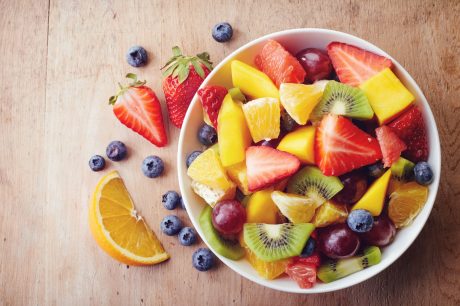 Colorful fruit in a white bowl on wood table